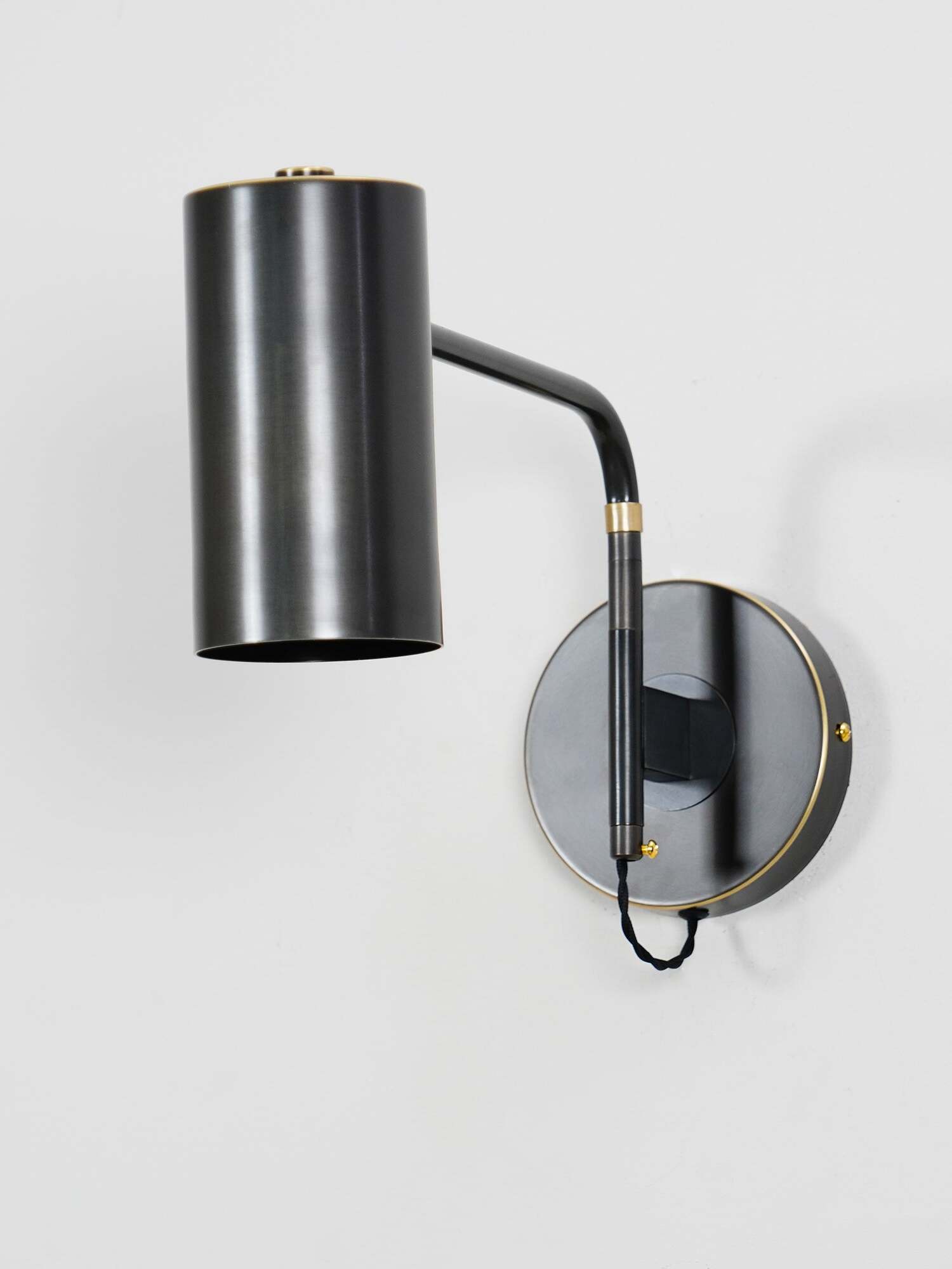 Black cylindrical shade on bent arm against white background