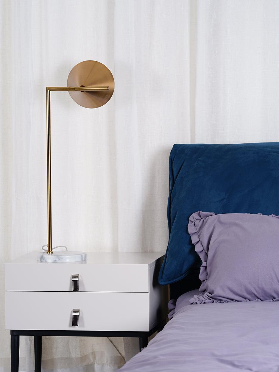 Cone shade turned sideways above white bedside cabinet