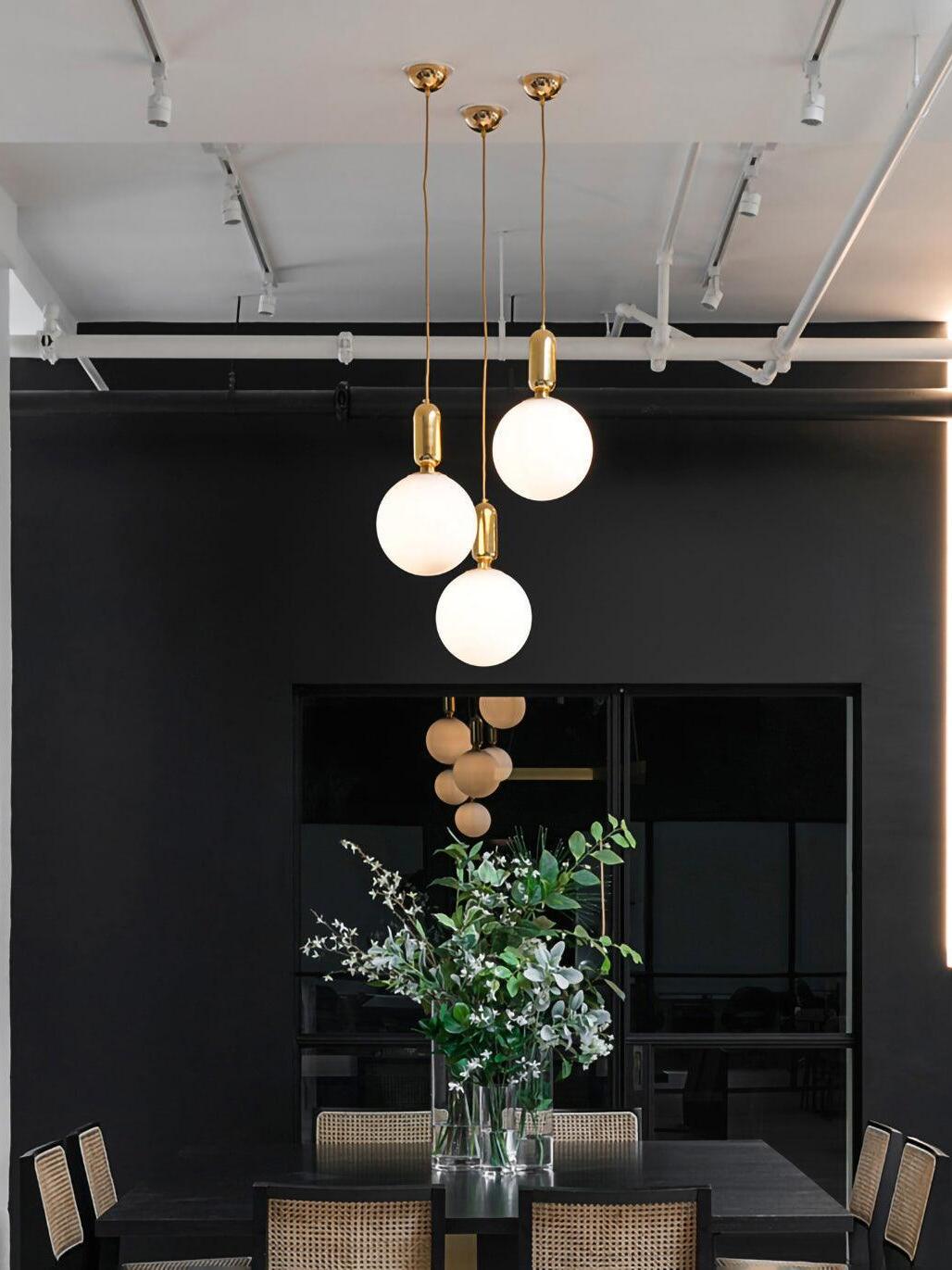 Three white globe pendants over a dark dining space