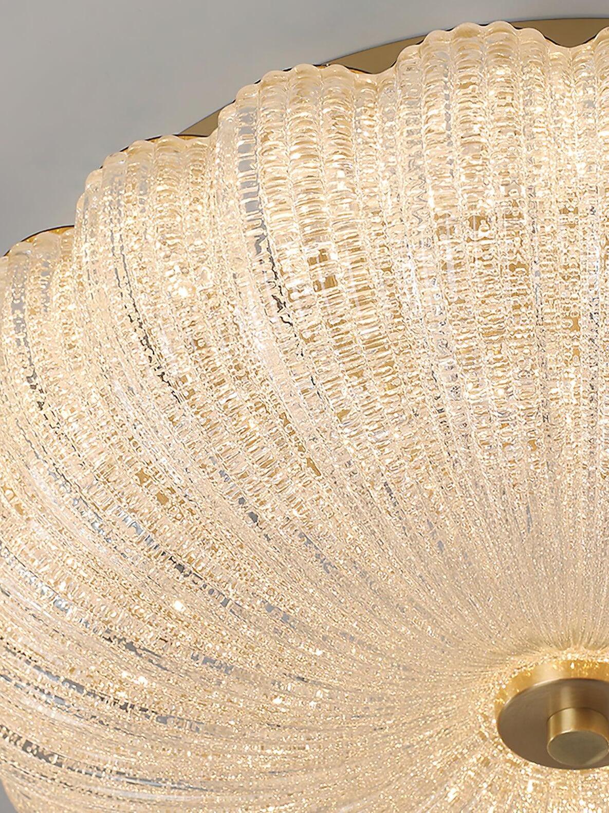 Close view of glowing textured glass ribs and scalloped edge beside a partially cropped gold-tone finial