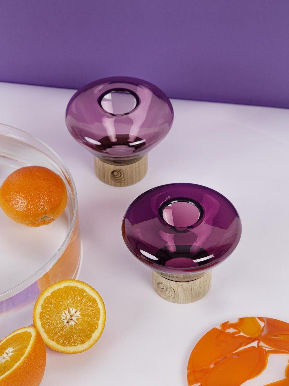 Top views of two purple rounded glass lamps near sliced oranges