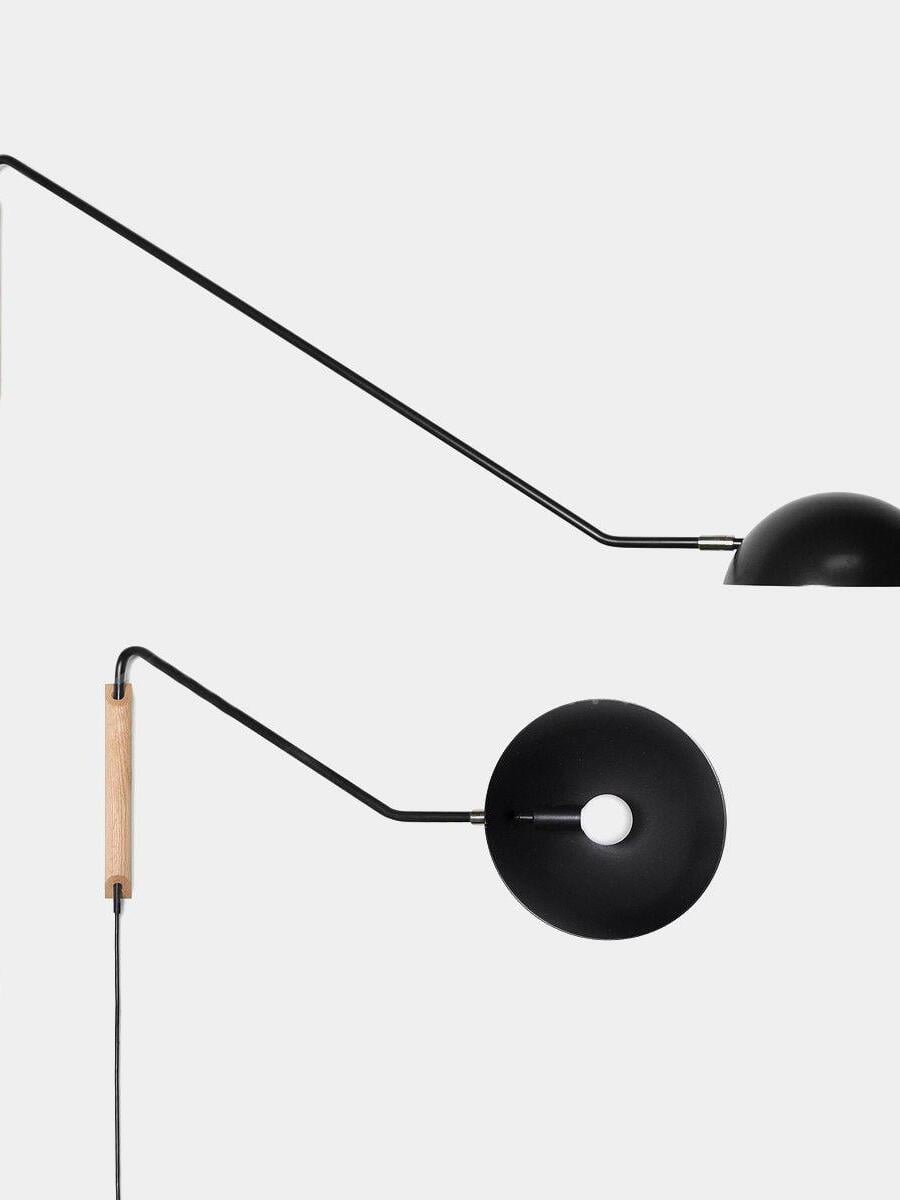Black dome lamp shown from the side and below on white, with long arm, light wooden mounting block and round bulb