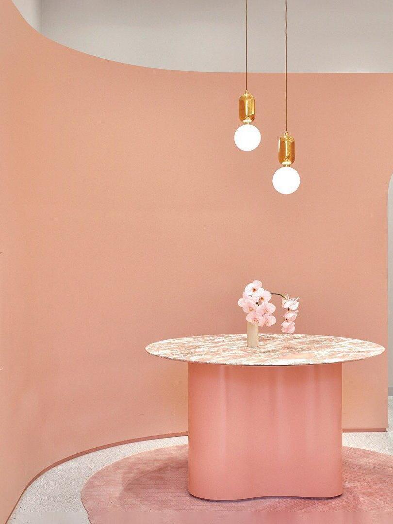 Two globe pendants over a round table against a pink wall