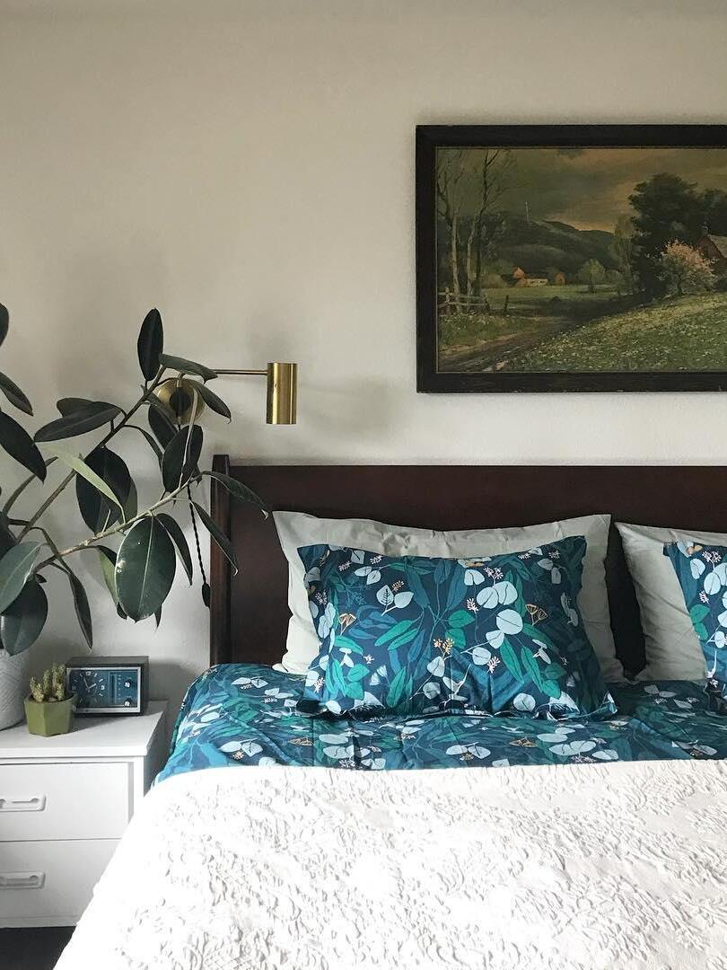 Two brass-tone bedside lights beneath landscape painting