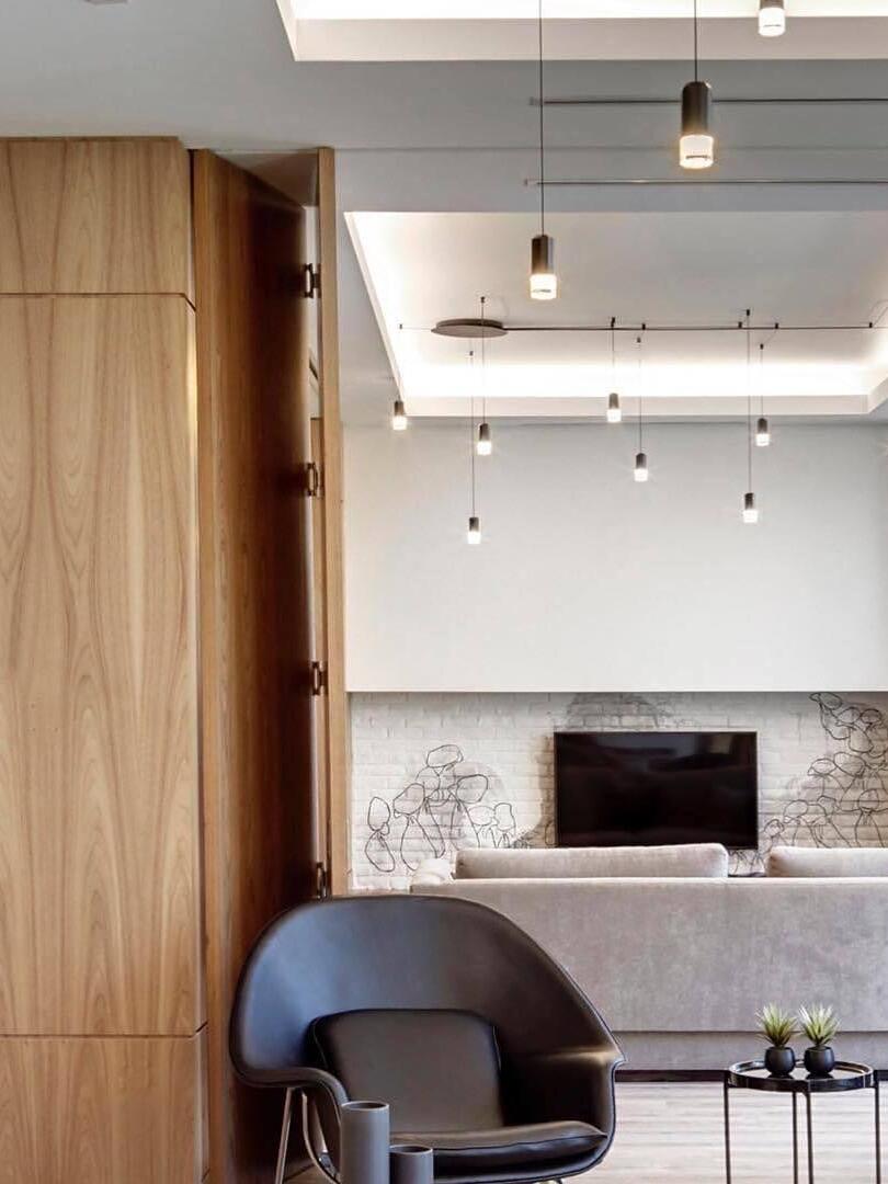 Cable-routed pendant heads across a living-room ceiling above an armchair and fireplace