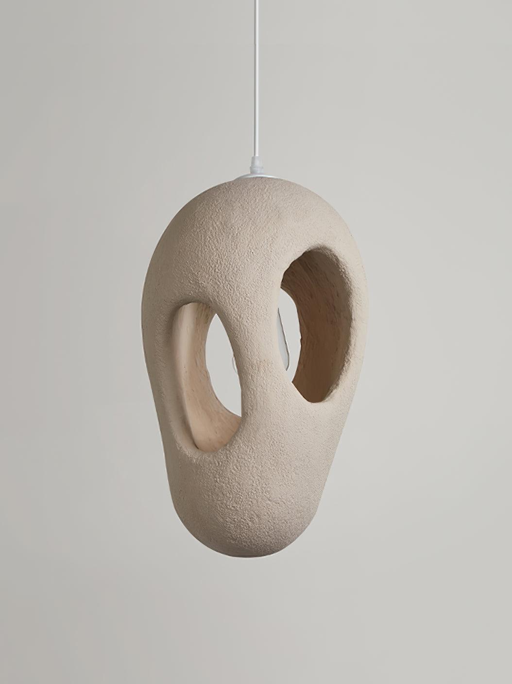 Unlit cream-looking elongated pendant with rough texture and two large through-openings on a White cord against Gray