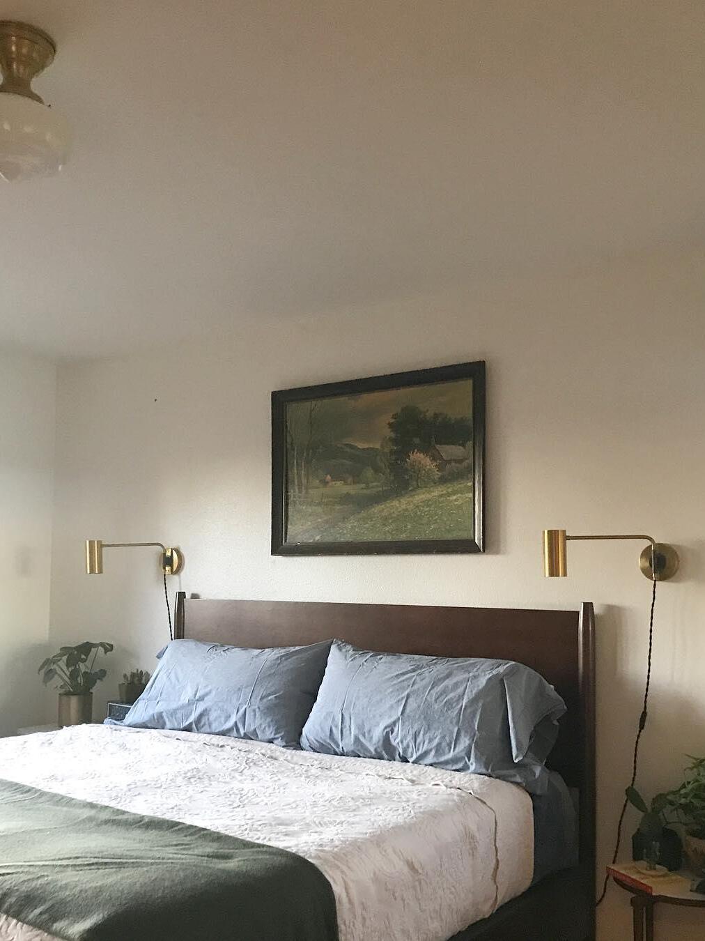 Bedroom with brass-tone wall lights flanking bed