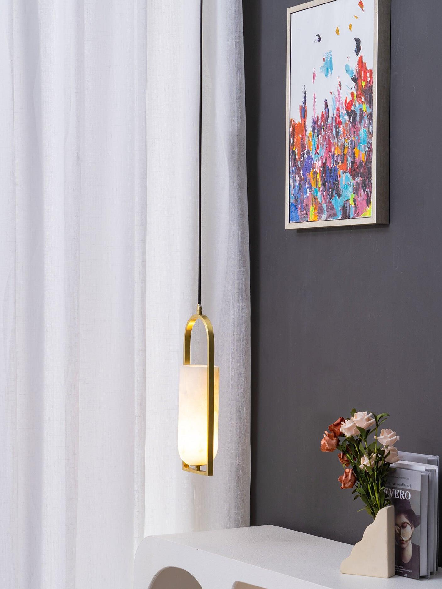 Long black suspension cord and glowing Melange shade beside a curtain and colourful artwork