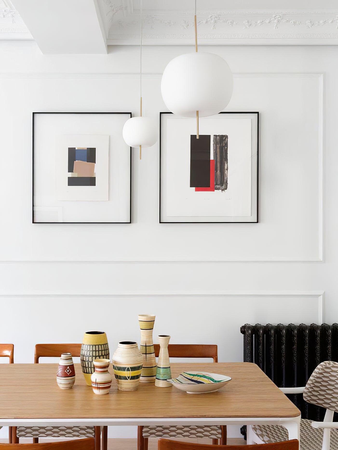 White glass pendant group above a dining table