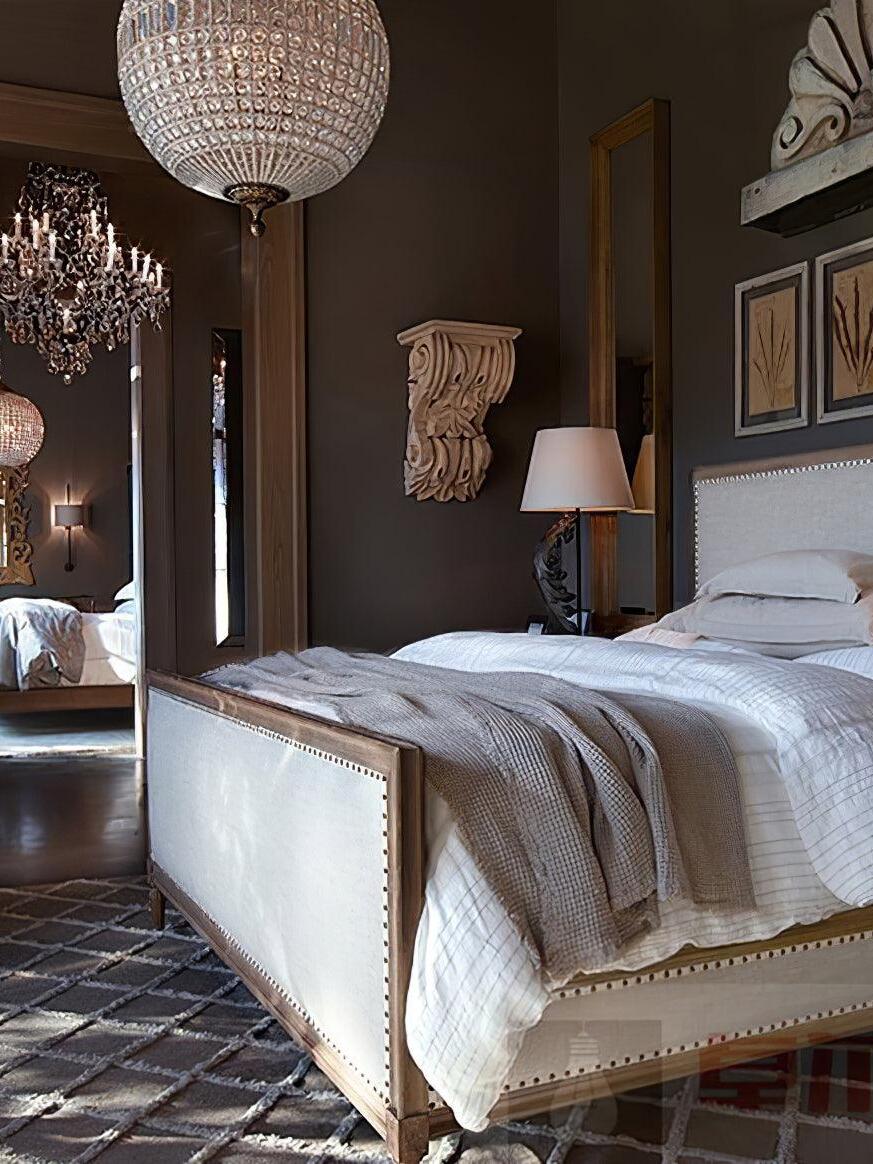Partially cropped crystal globe above an upholstered bed in a traditional bedroom with a mirror and bedside lamp