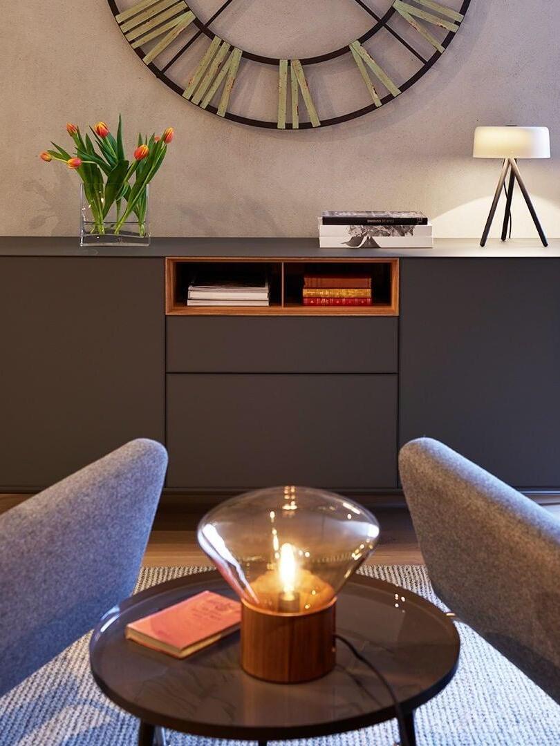 Lit amber-smoky glass lamp on round side table with book between chairs