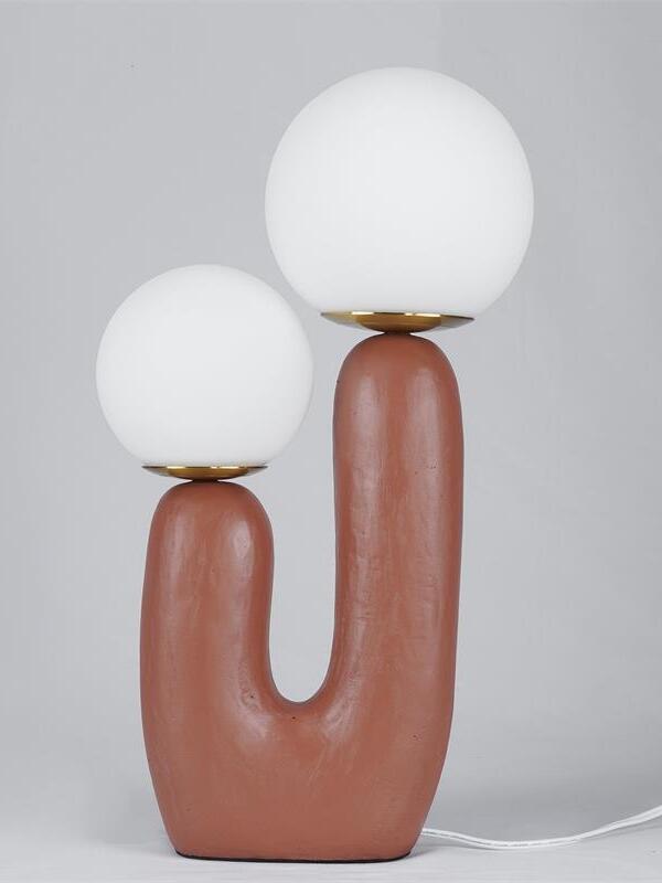 Terracotta Oo Rough twin-globe lamp against grey, white opal globes, warm-metal collars and cord to right