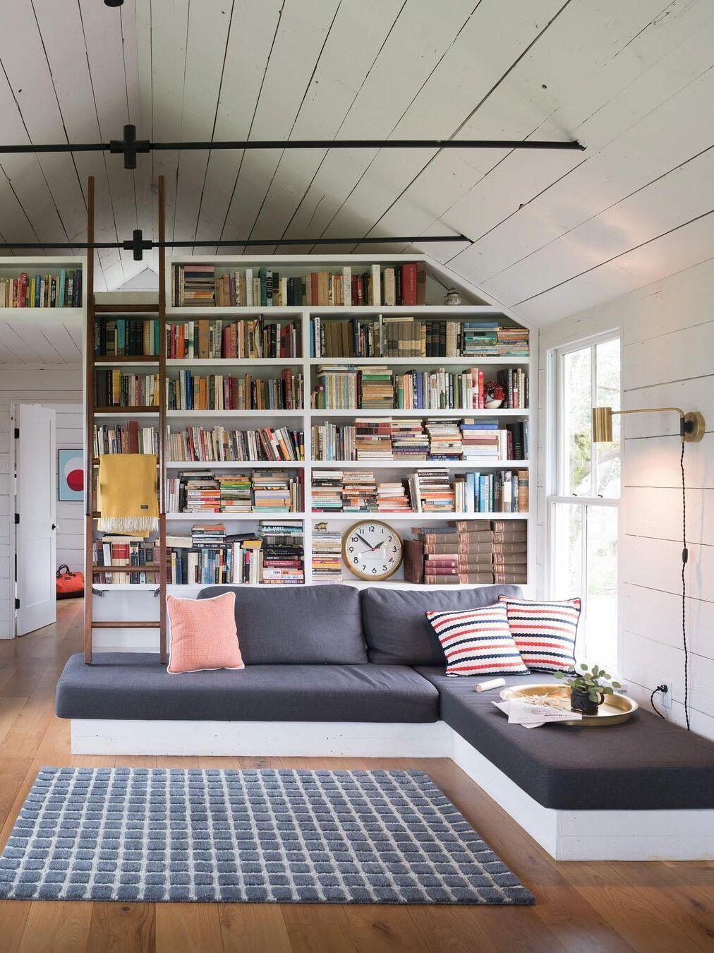 Brass-tone wall light beside bookcase and sofa with plugged cord