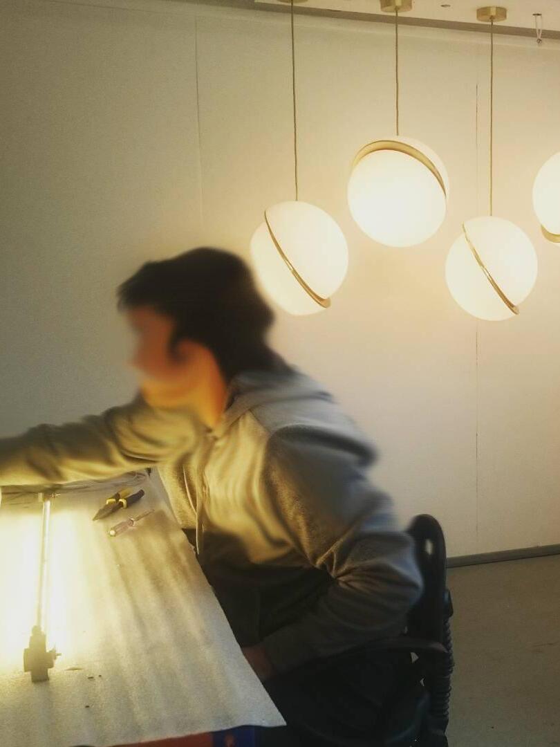 Several lit Crescent globe pendants above a workbench with a blurred person in the foreground
