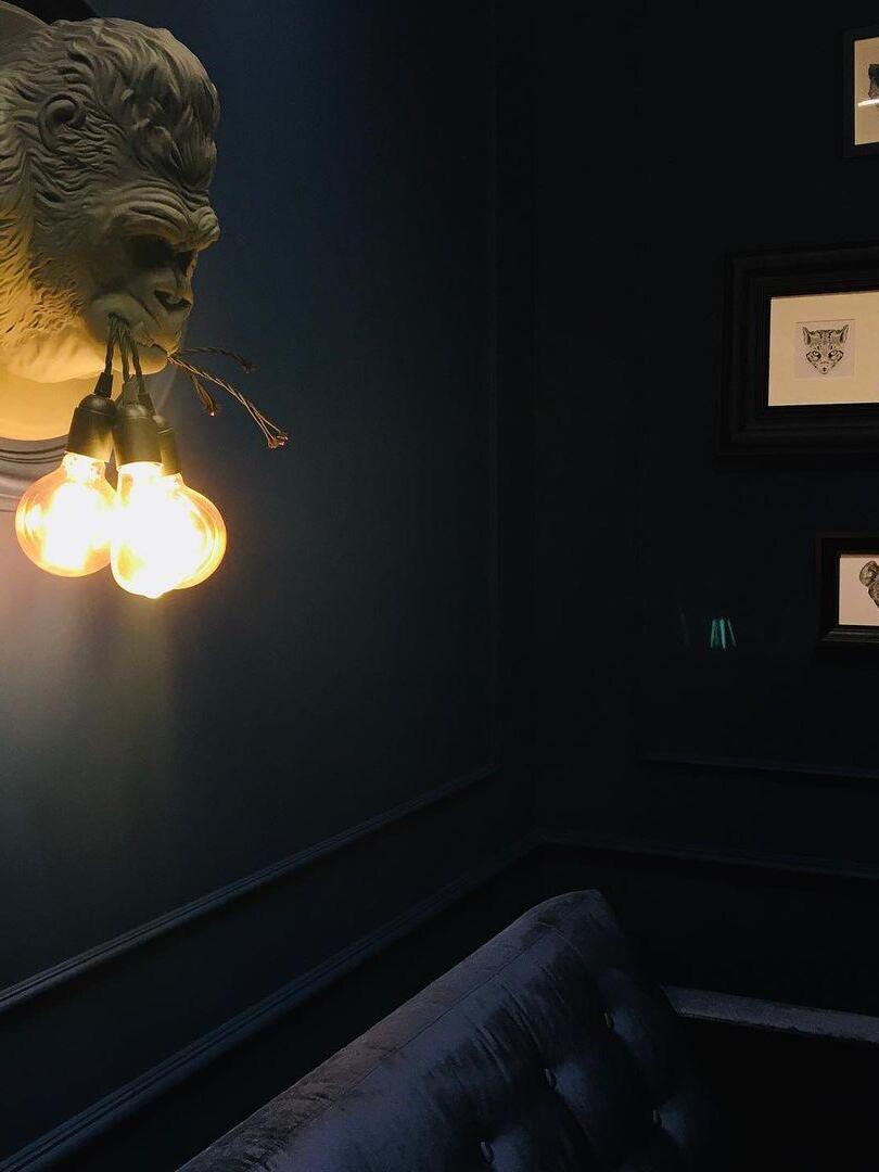 Partial grey gorilla relief with glowing round bulbs above dark seating