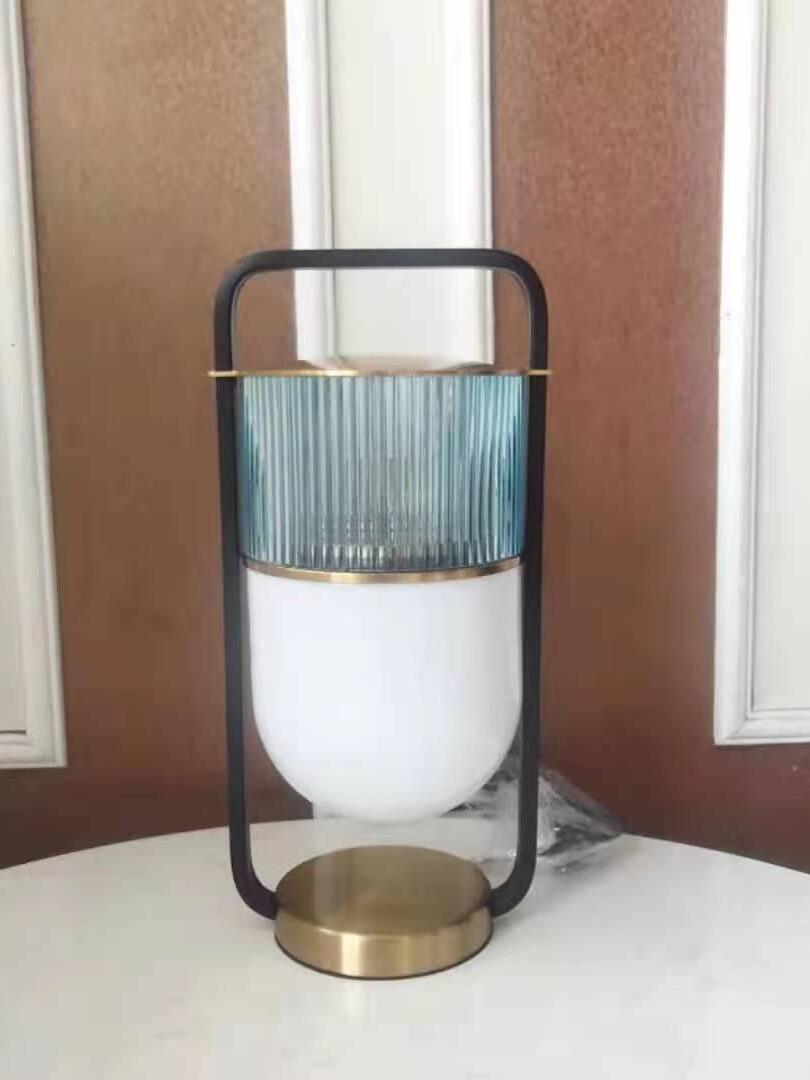 Unlit Xi lamp with grey-blue ribbed glass, white lower shade and gold-tone base on a window sill