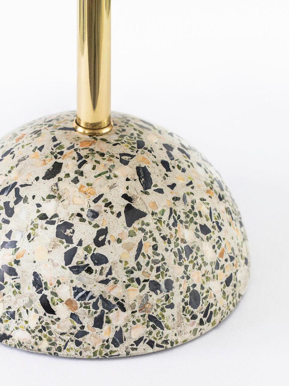 Close terrazzo dome base where reflective gold-tone stem joins speckled surface