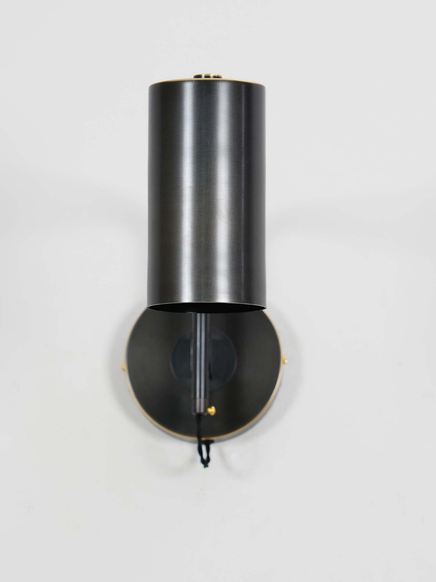 Black cylinder aligned closely in front of round mounting plate
