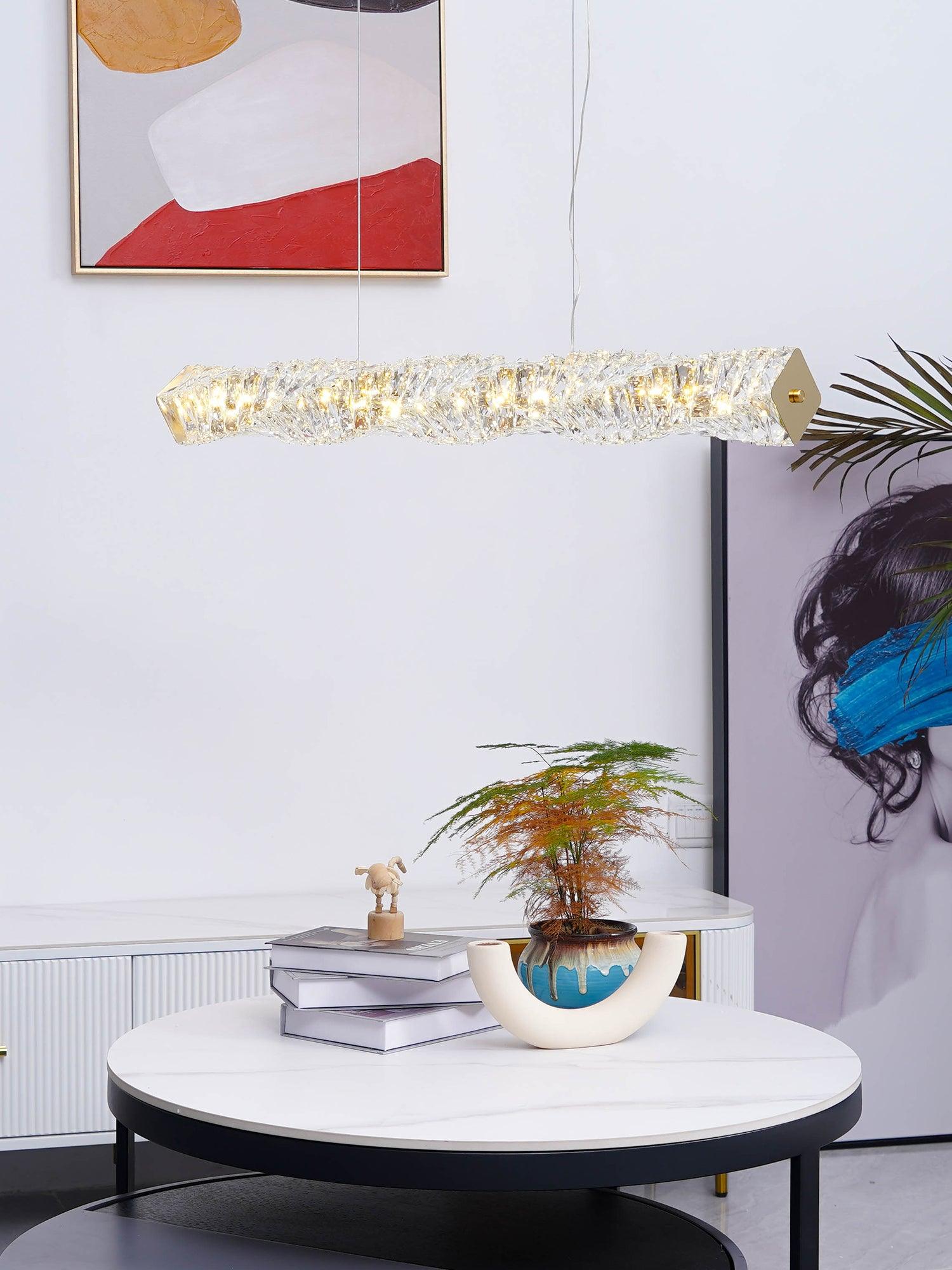 Crystal pendant above a white coffee table with a plant beneath red abstract wall art