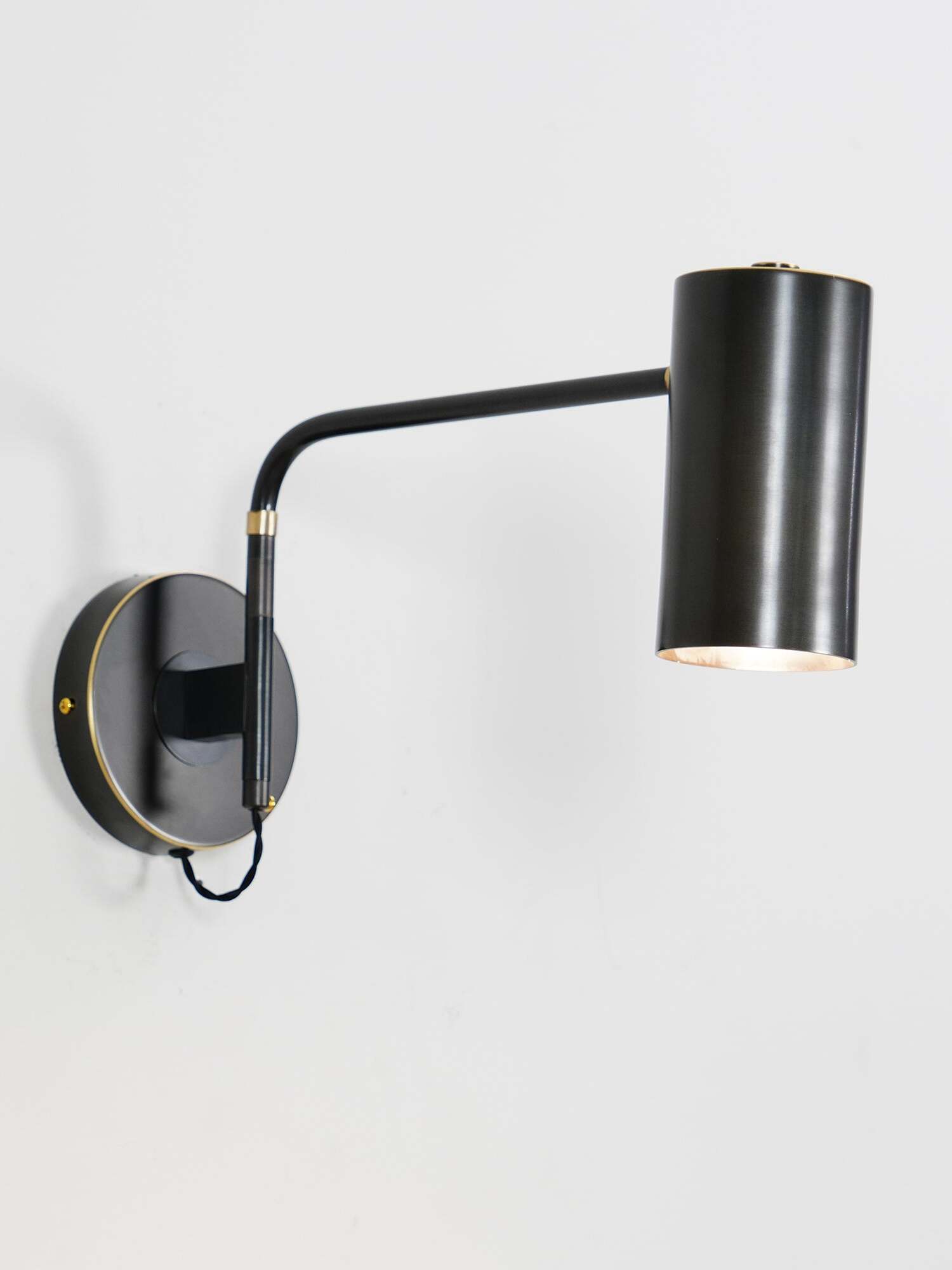 Black cylindrical wall light with bent arm and round plate