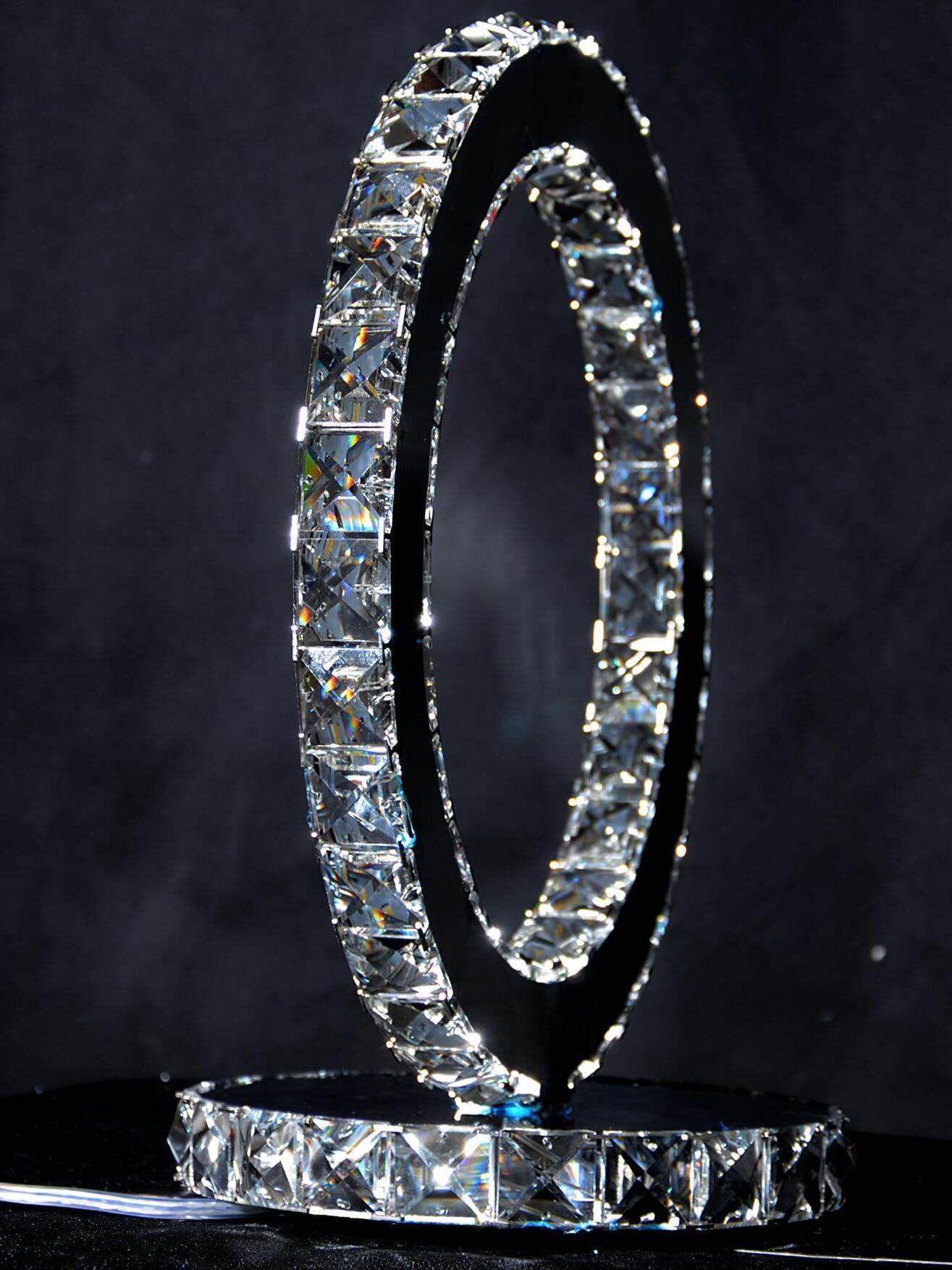 Angled side view of an illuminated upright ring and round base against a dark background