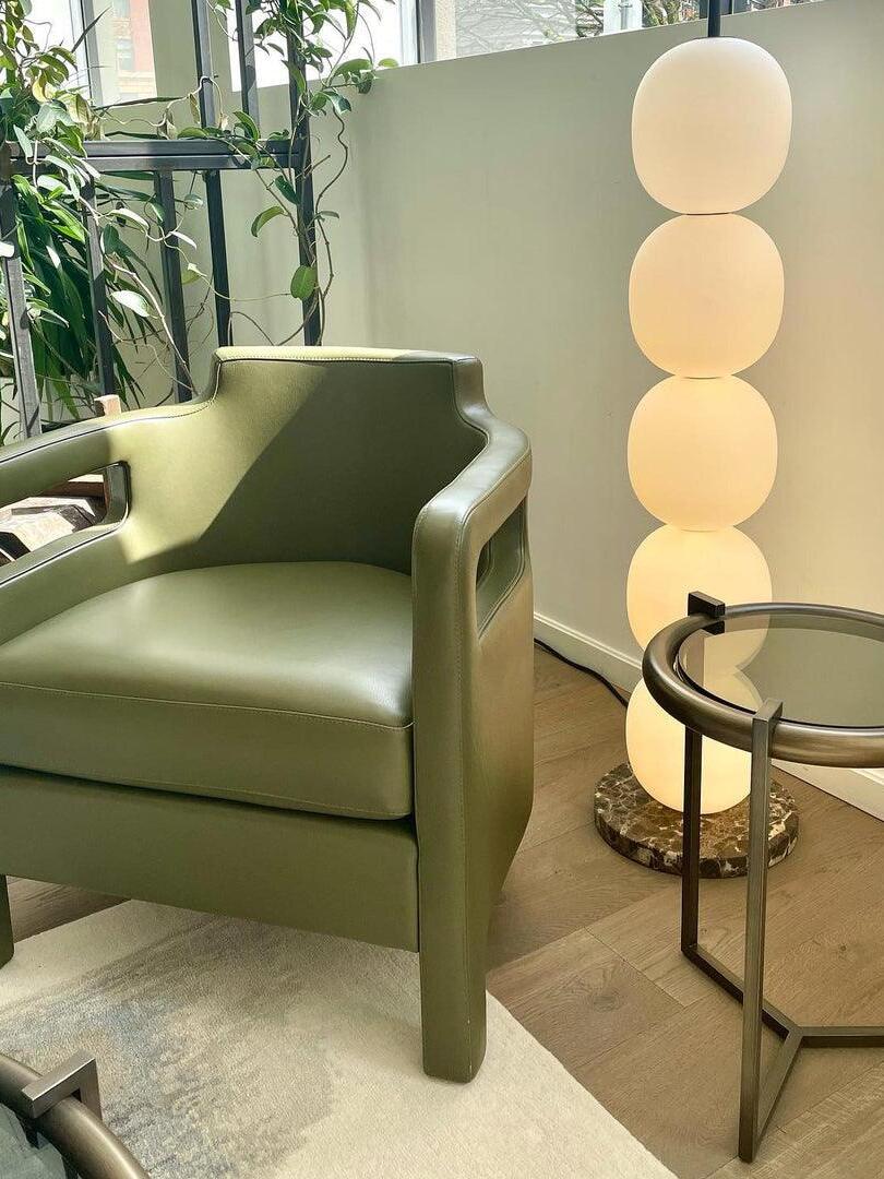 Illuminated globe column beside green armchair