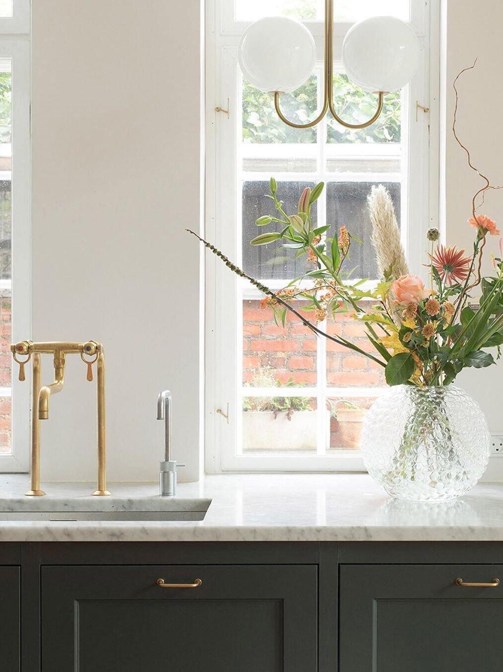 Brass curved-arm pendant near a kitchen window