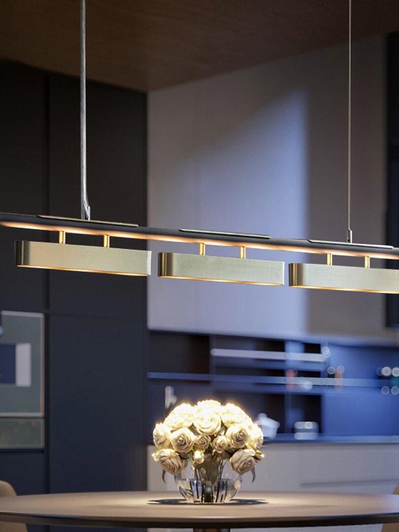 Colt brass-module pendant above a round table and vase of flowers in a modern dining room