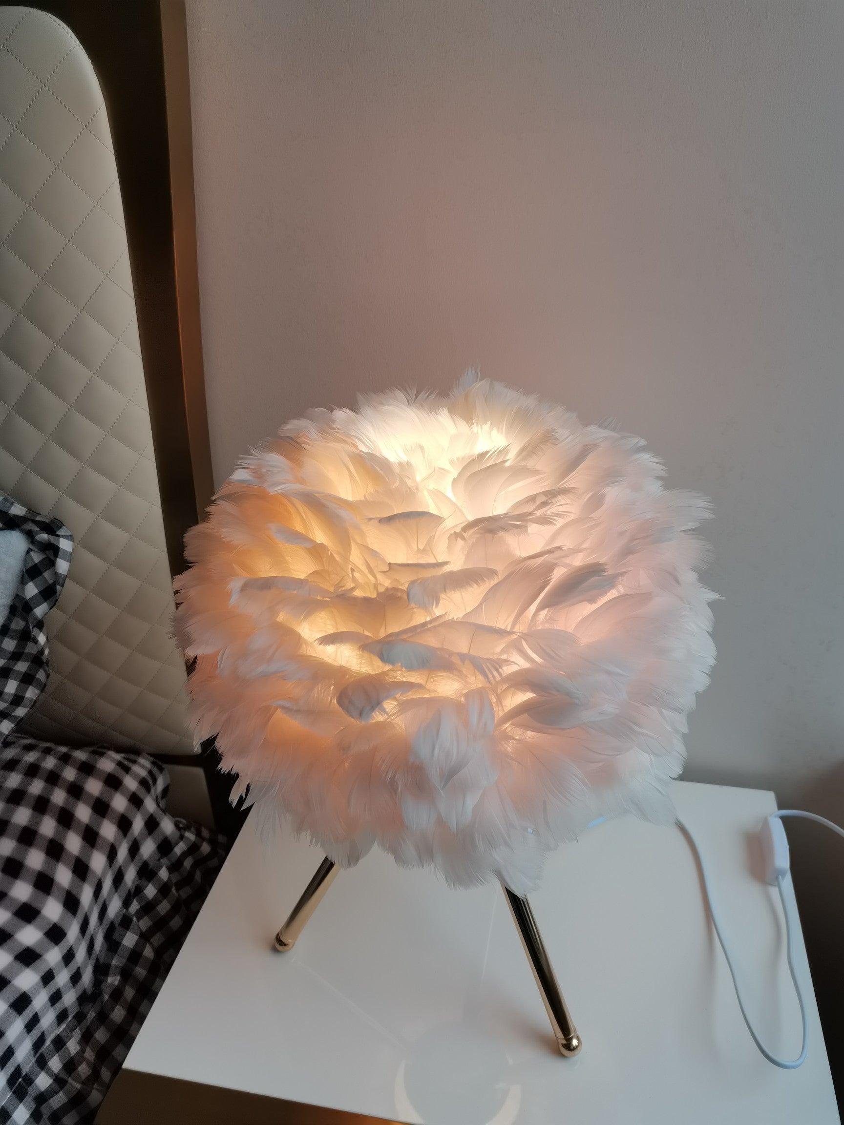 Pale pink feather lamp beside upholstered headboard