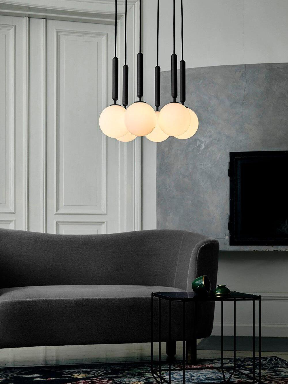 White hanging globes and black stems above a sofa