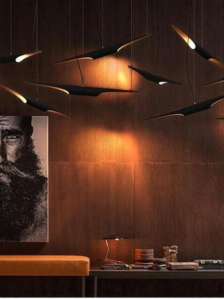 Pipe pendants above a dark wood-paneled room with portrait, orange seat and a table