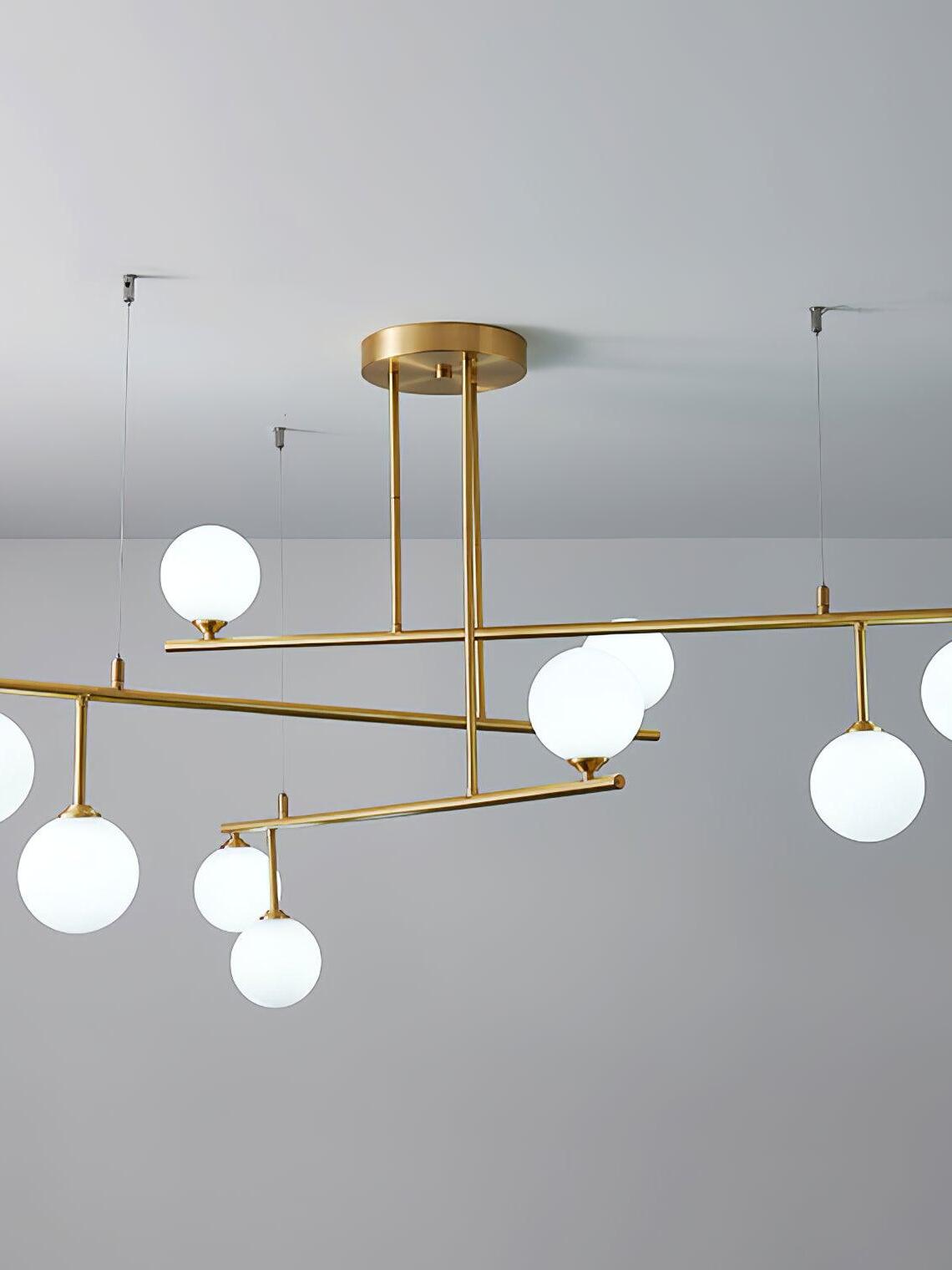 Close view of the wide Arteriors tiered globe chandelier, with staggered brass-tone bars and ceiling support wires