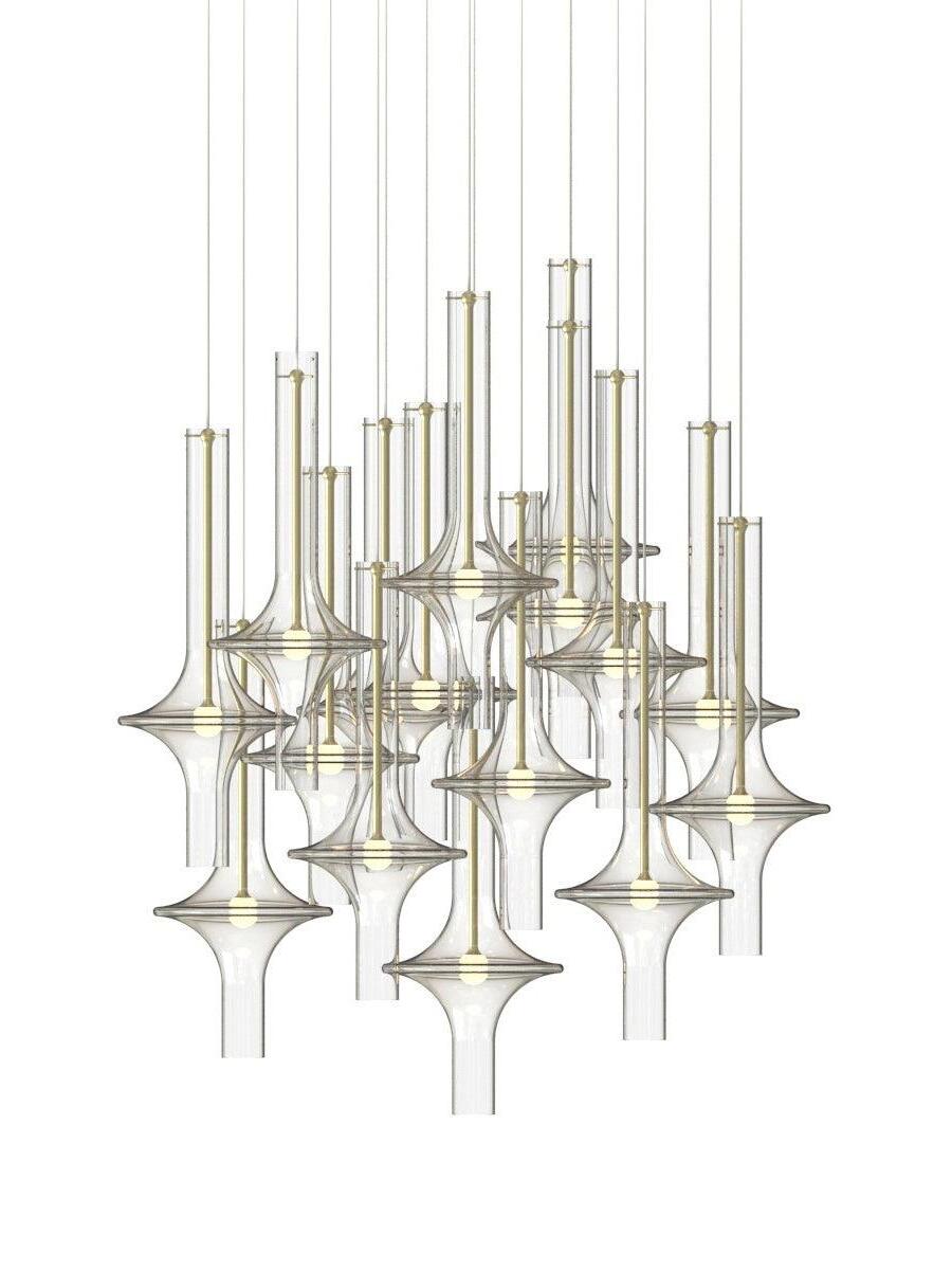 Large arrangement of clear glass pendants with gold-tone stems, flared rings and numerous suspension cables on white