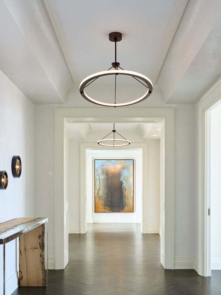 Black illuminated circular pendant repeated along hallway