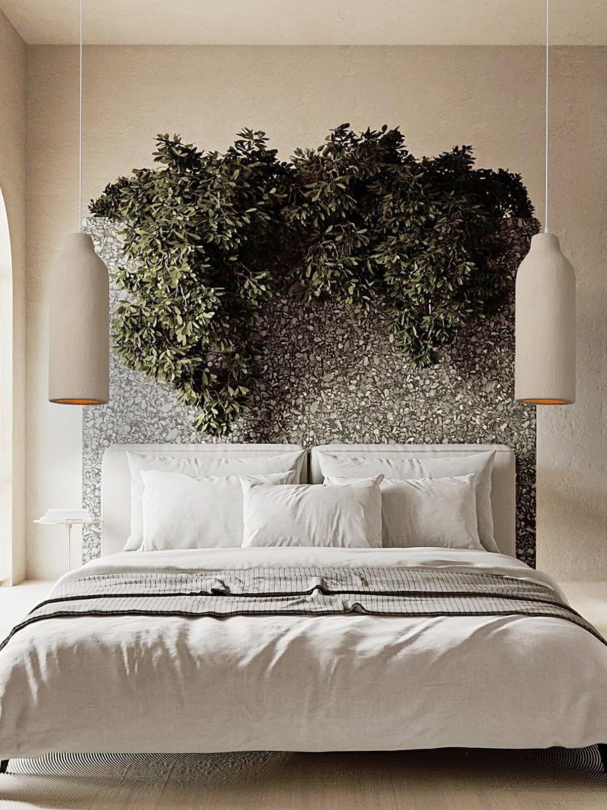 Two narrow bottle pendants beside a white bed with a textured grey headwall and trailing foliage