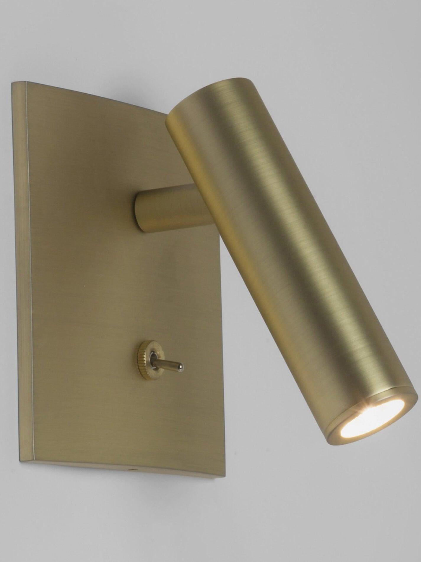 Gold-tone Enna angled cylindrical wall light with square plate and lower toggle against pale grey background