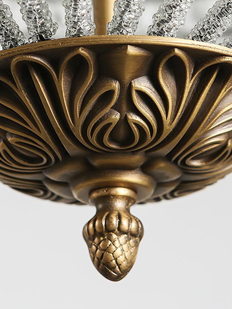 Close view of a carved gold-tone bottom bowl and acorn-like finial beneath beaded cage ribs