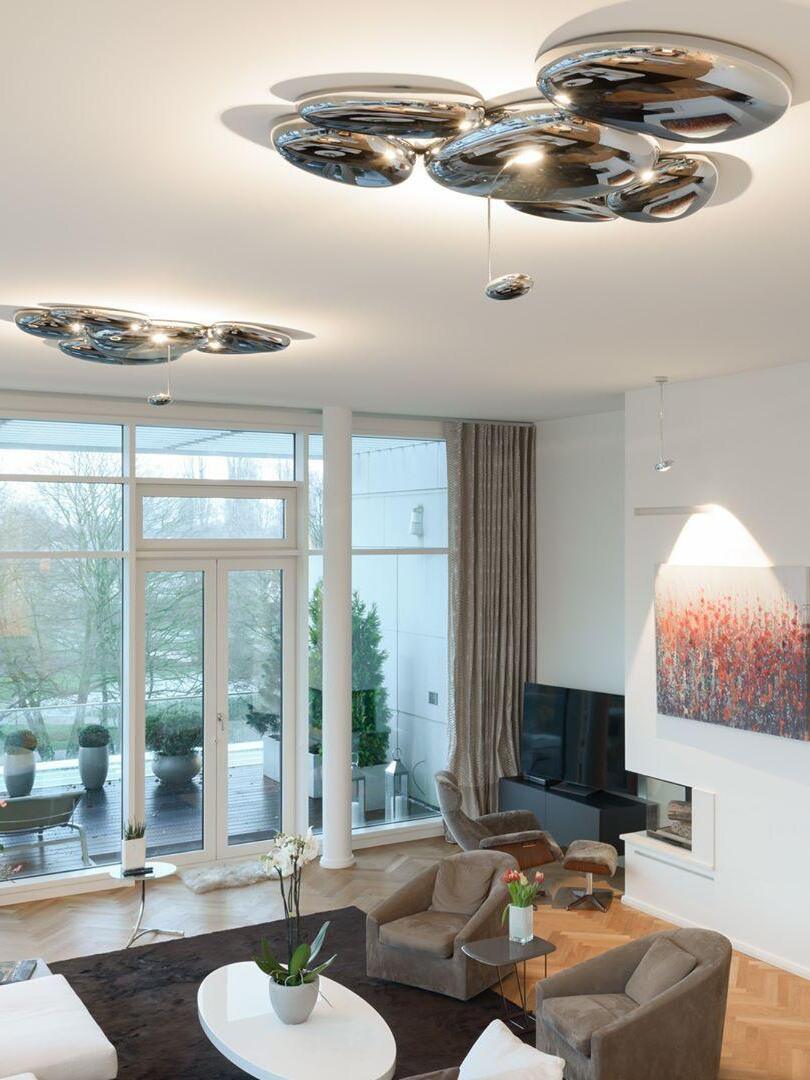 Two reflective ceiling clusters in glazed seating room with books and artwork