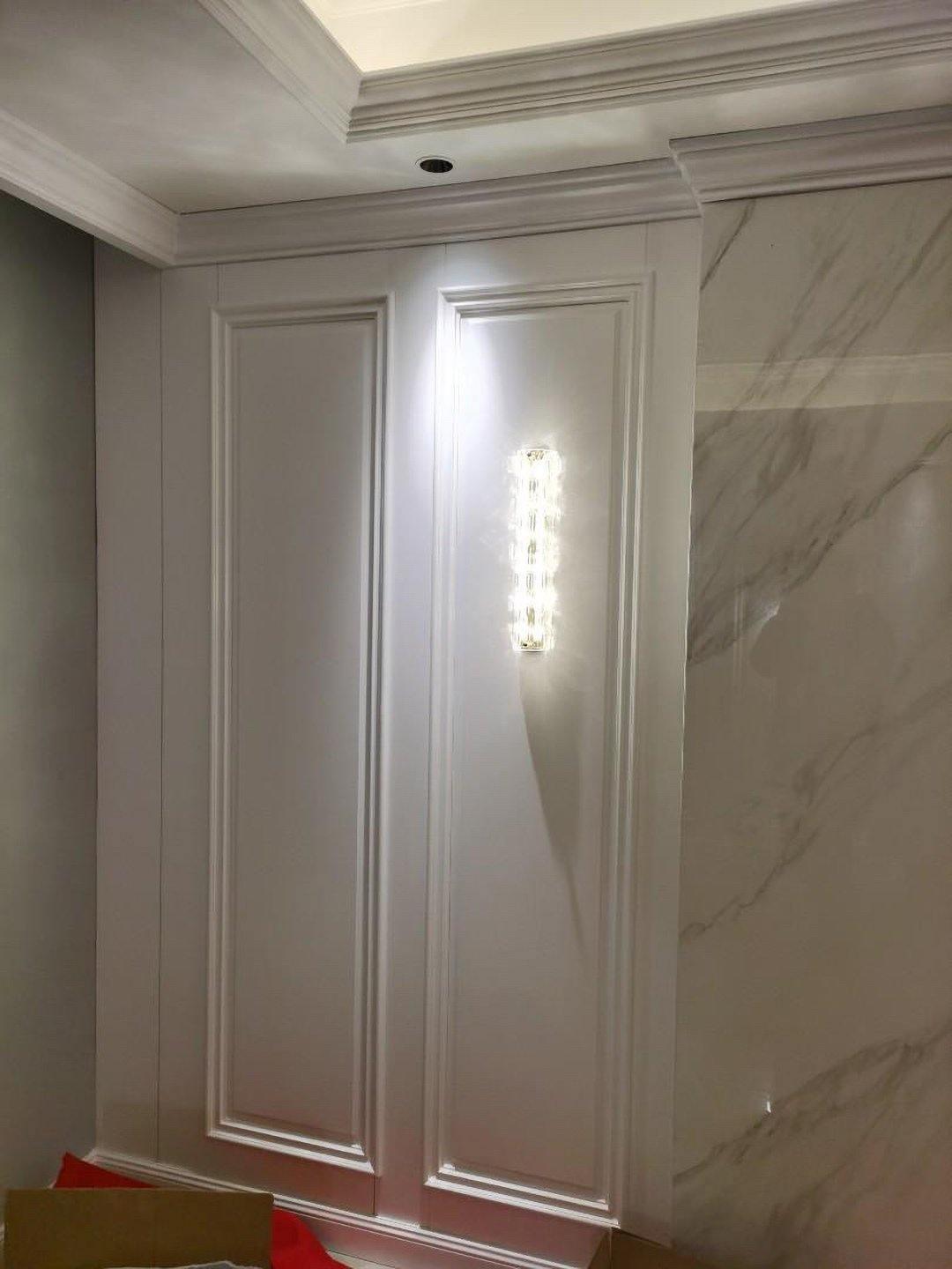 Glass wall light on white panel beside marble-patterned wall