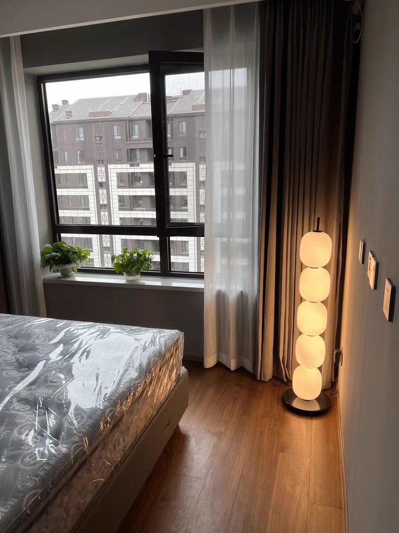Five-globe lamp beside bed and window
