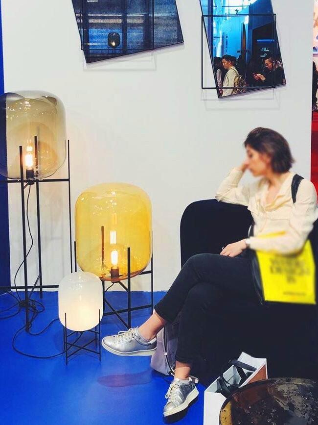 Display of large and small glass lamps near a seated visitor.