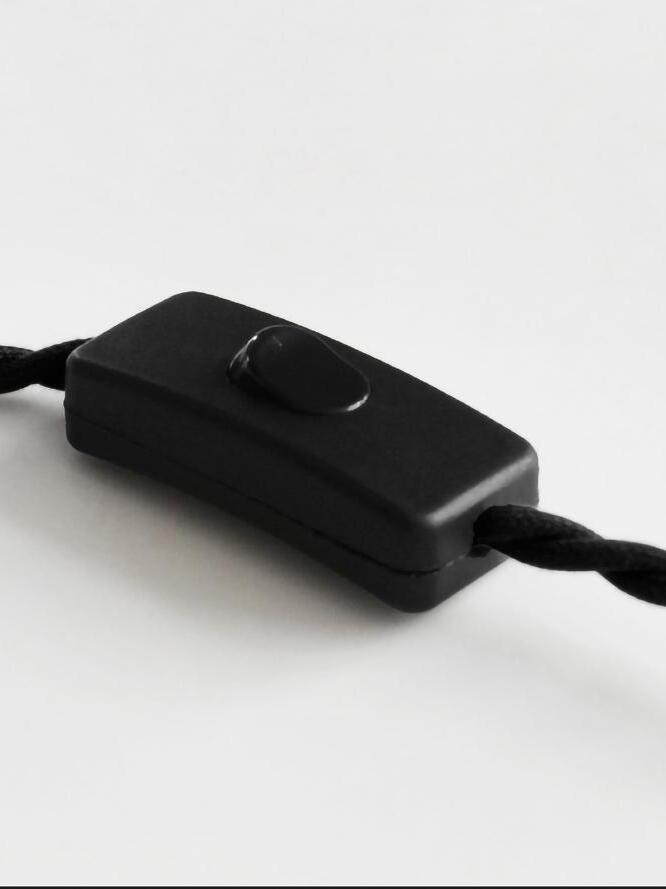 Black inline push-button switch on twisted cord