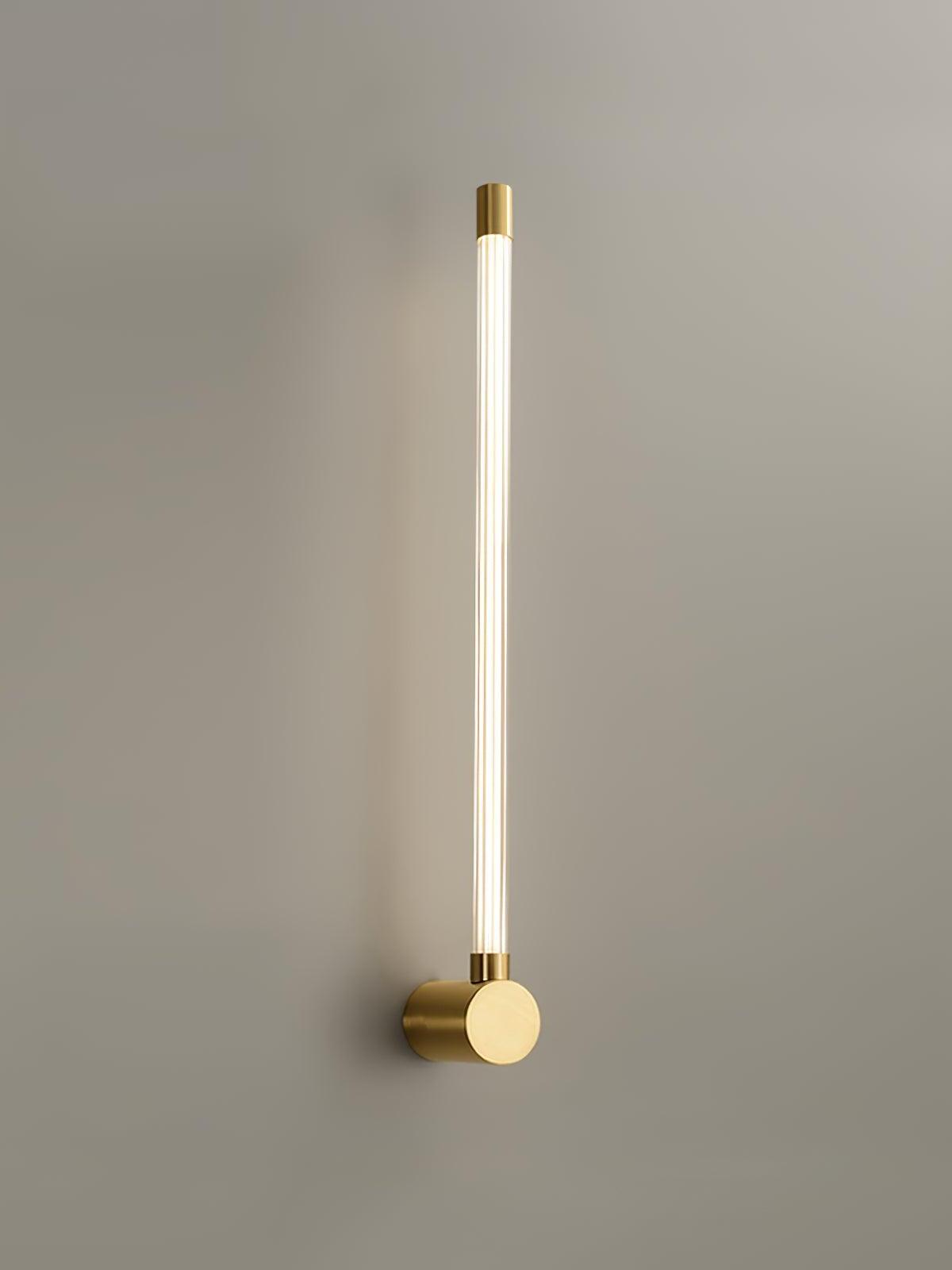 Brass-tone single upward ribbed tube sconce with a round mount and capped upper end