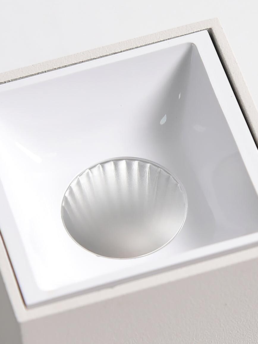 Macro view of a white square recessed cup and circular reflector inside a white spotlight housing