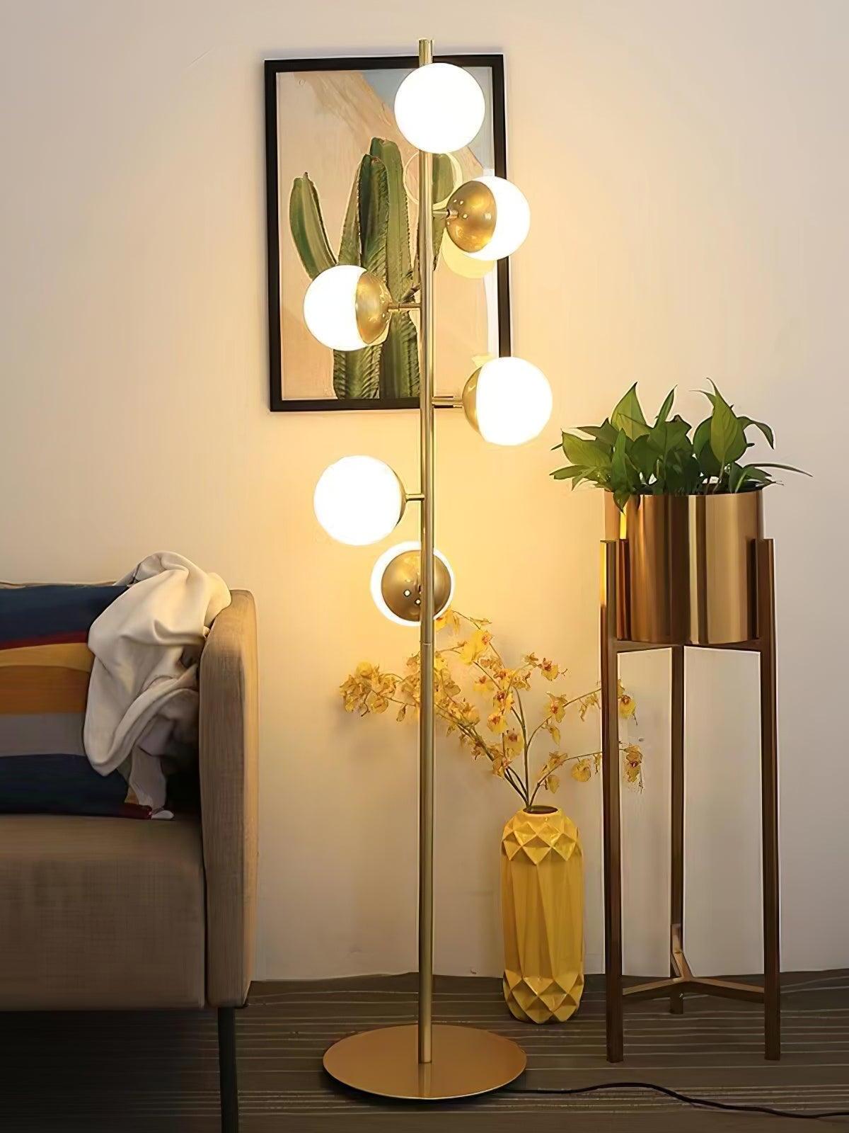 Tall gold globe lamp beside sofa and plant