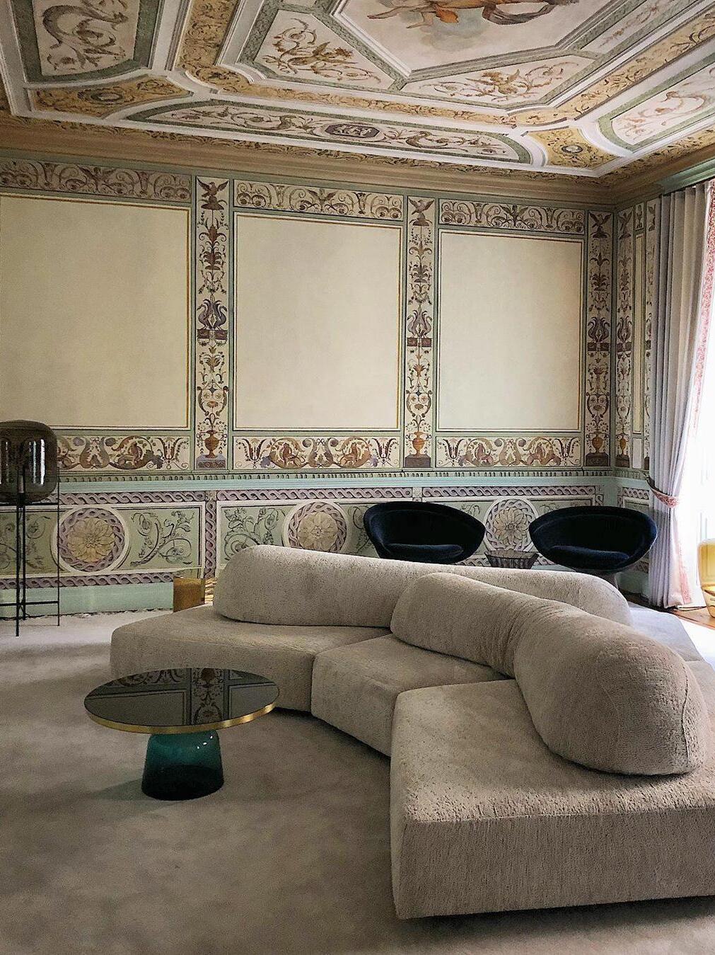 Smoke-toned glass lamp near a curved sofa in an ornate sitting room.