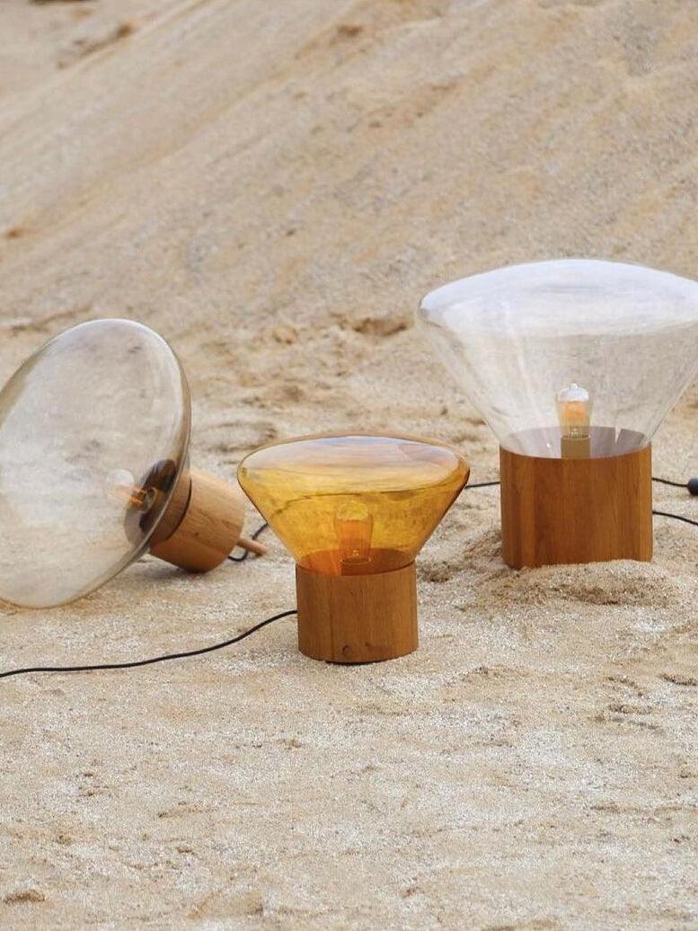 Clear and amber glass lamps on rough pale stone surface with one lying sideways
