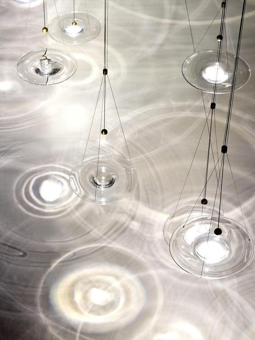 Many lit glass discs reflecting rings on floor