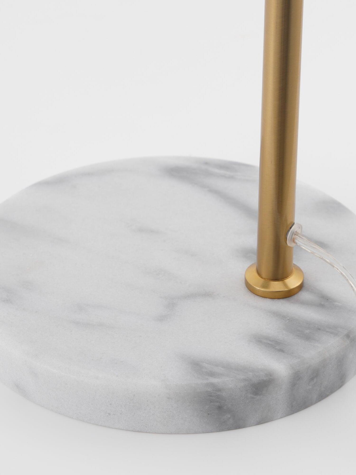 Grey veins in pale marble disk around gold-tone lamp stem