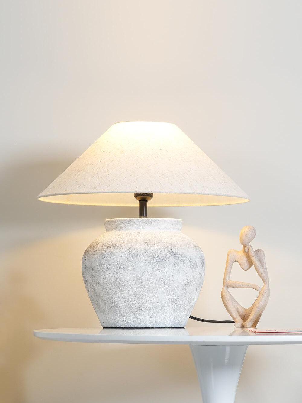 Pale ceramic urn lamp on white side table